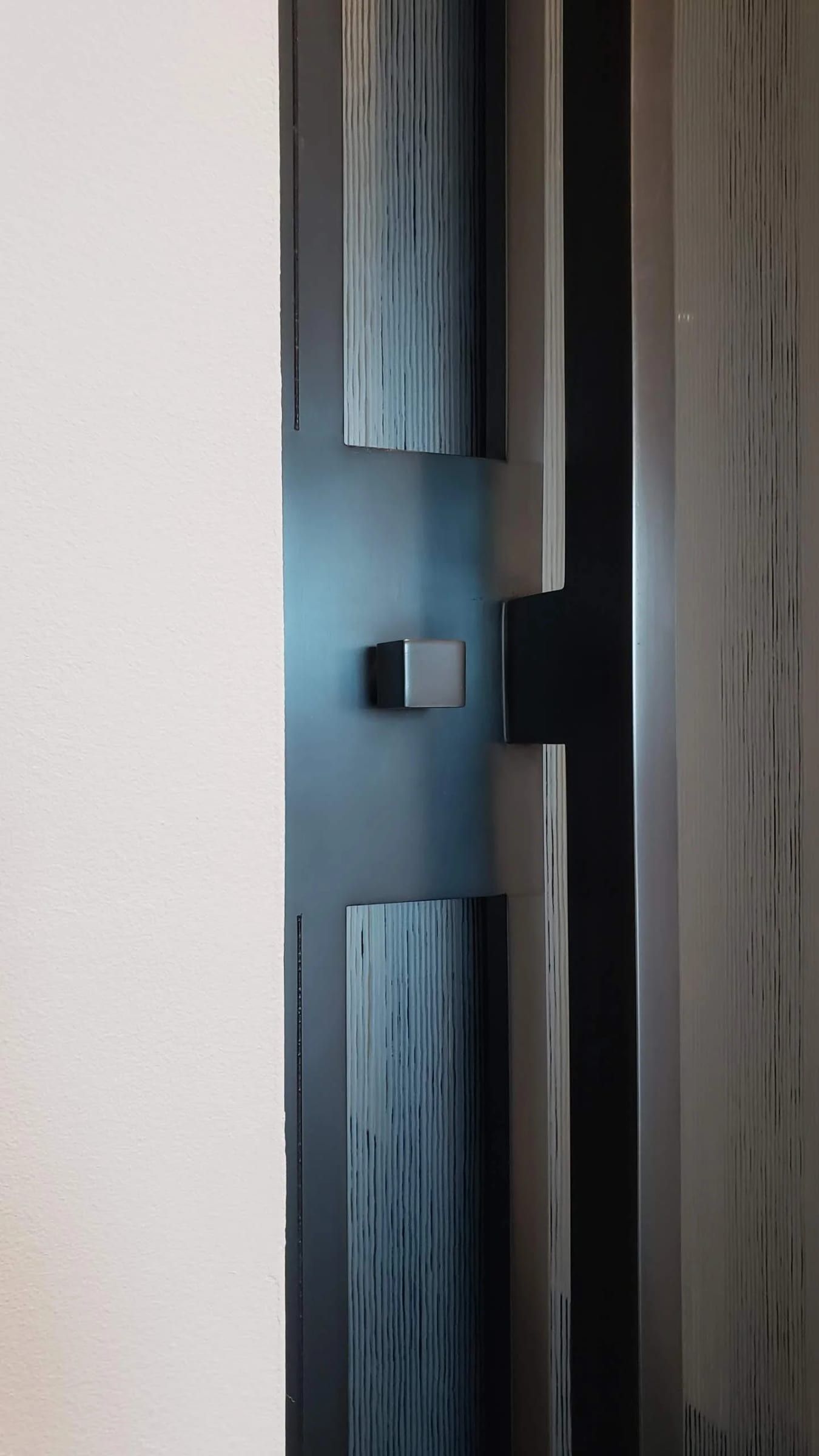 Blackened stainless door pull with a wood inset, close detail