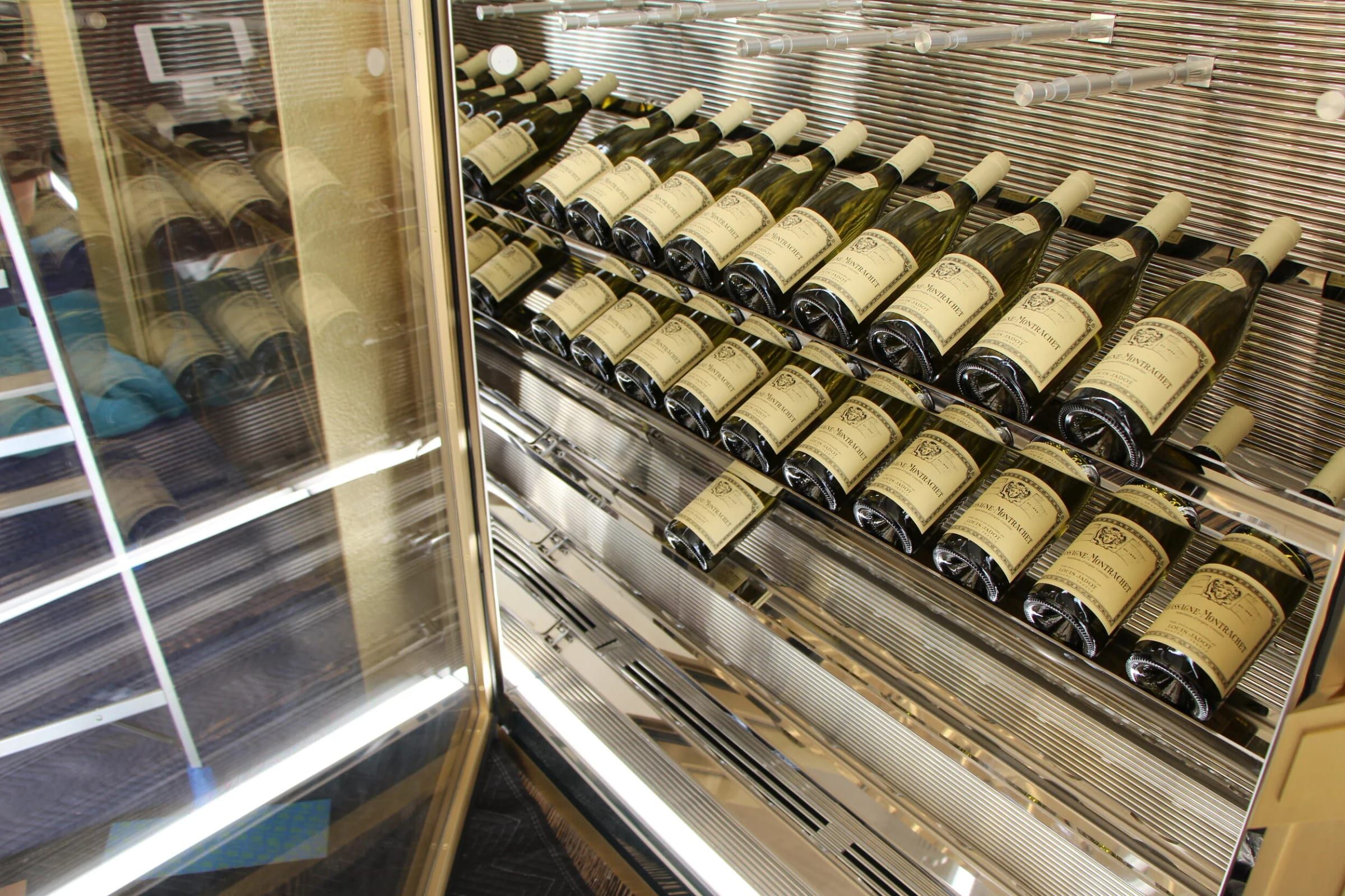 Wine bottles stored behind brass-framed glass