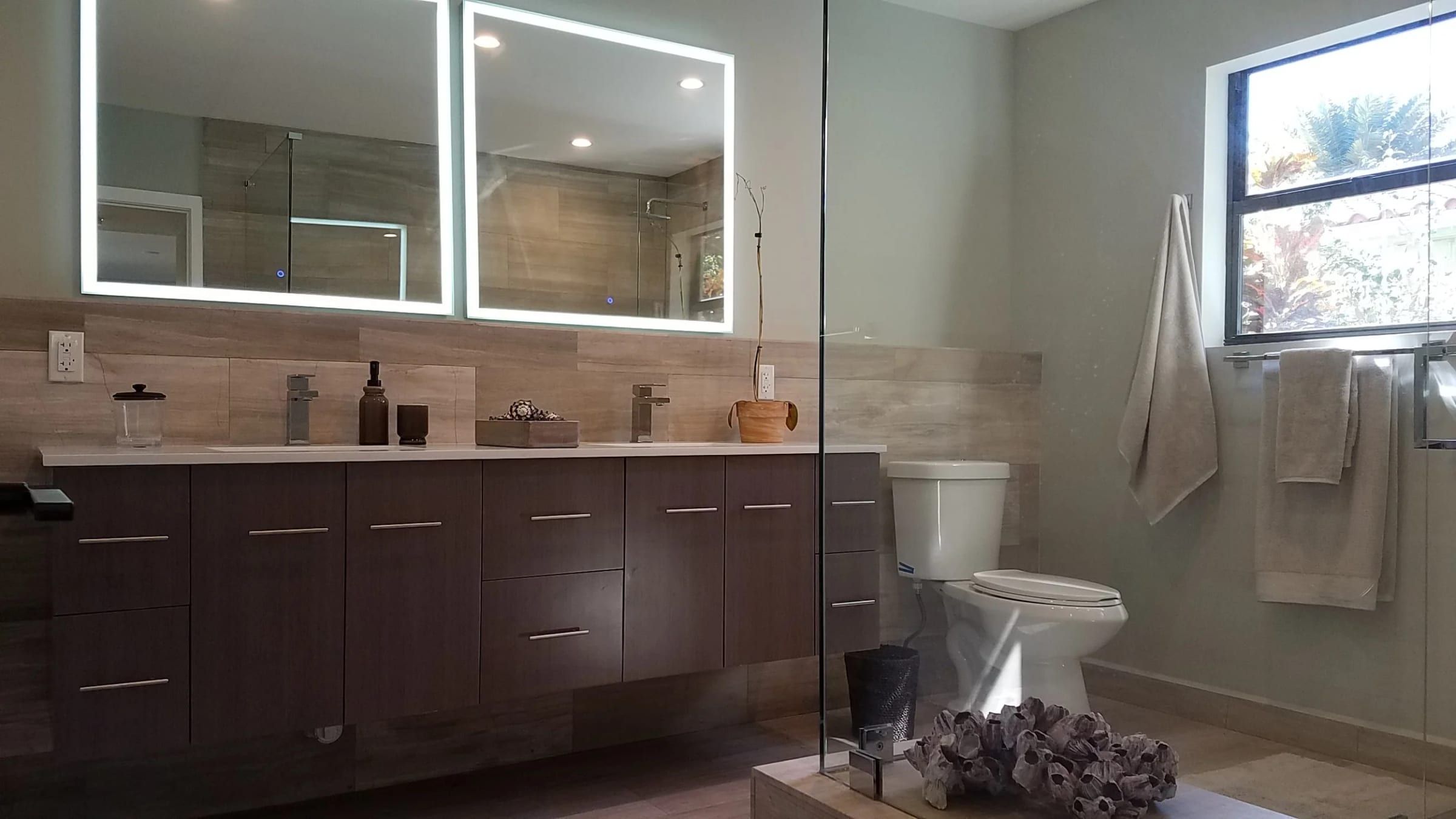Bathroom with a dark wood vanity and backlit mirrors