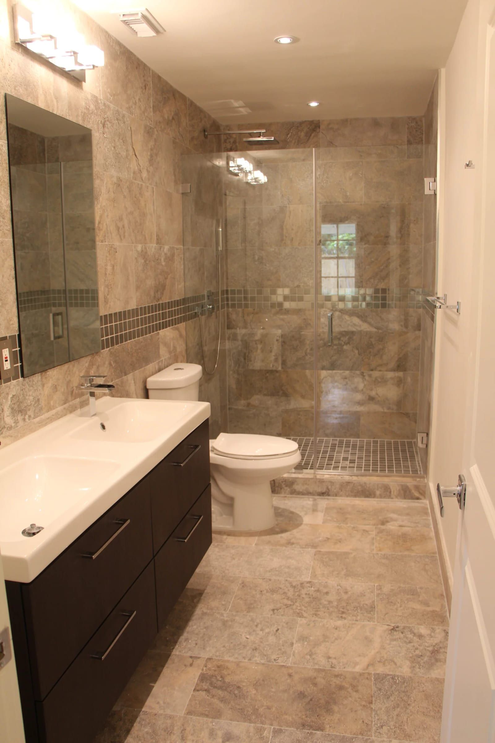 Travertine bathroom with a glass shower and floating vanity