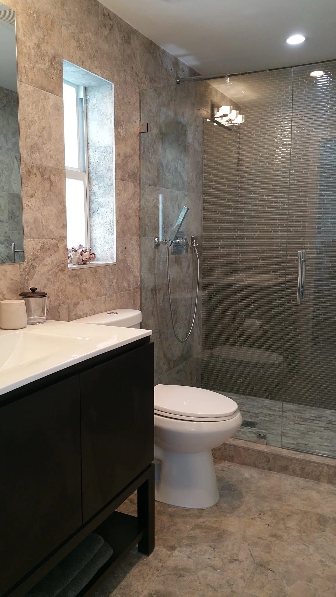 Stone-tiled shower beside a dark wood vanity